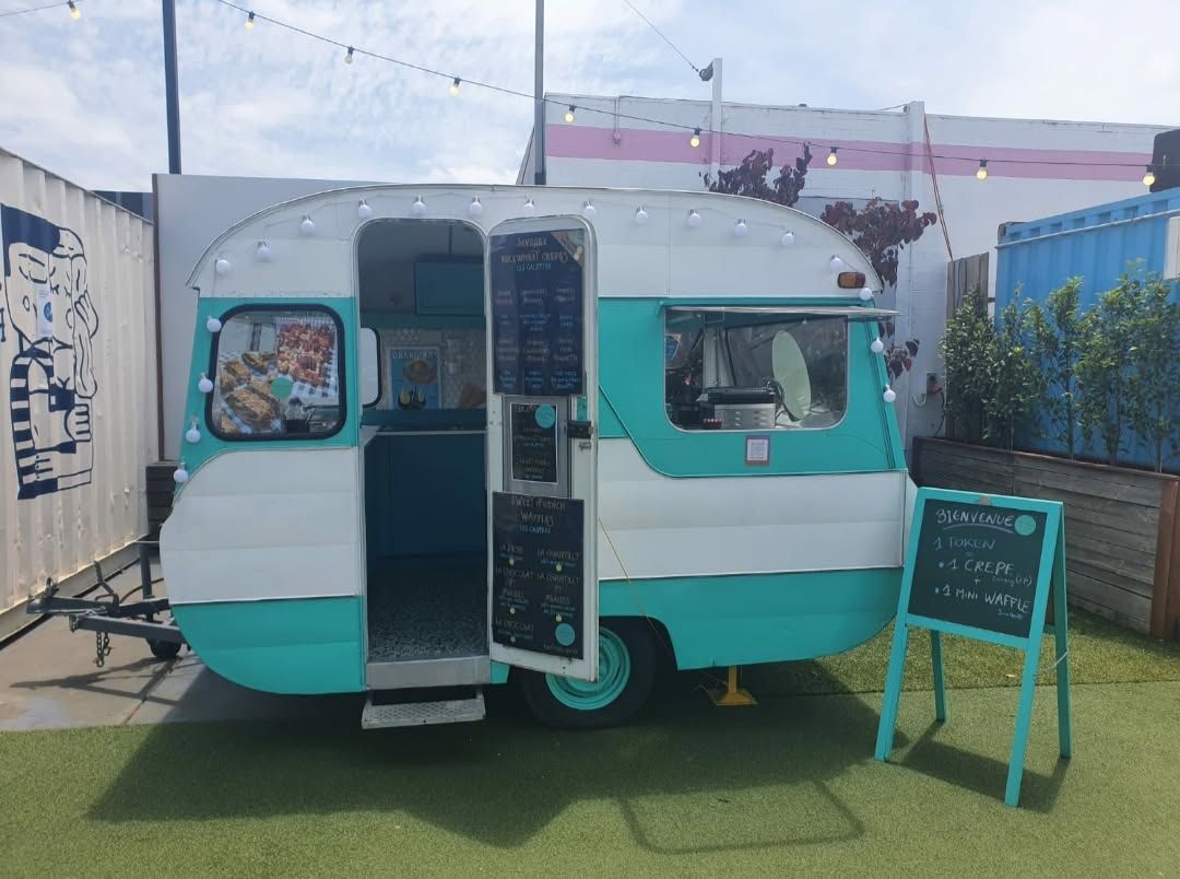 Bright side view of the turquoise-and-cream La Belle Epoque French food caravan with welcome sign
